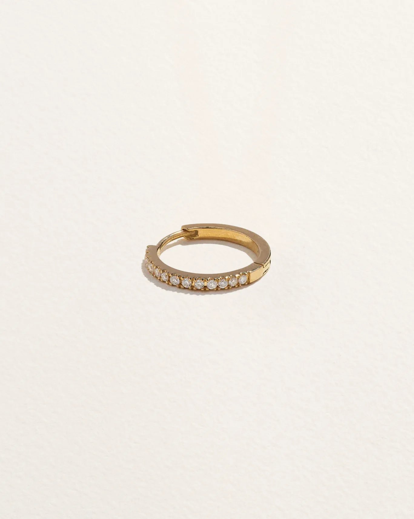 14K yellow gold huggie piercing with pavé diamonds, 10mm inside diameter, shown flat from above displaying hinge clicker closure