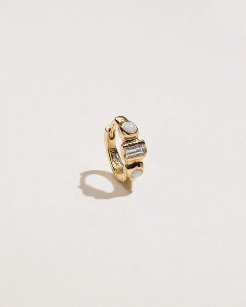 14K yellow gold piercing huggie with two Gilson opals and a baguette diamond, shown from an angled front view