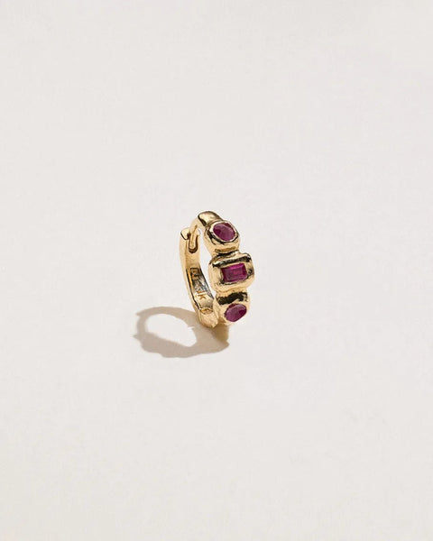 Angled 14K yellow gold Molten Assemblage Huggie with two vivid rubies framing a baguette ruby in molten bezel settings