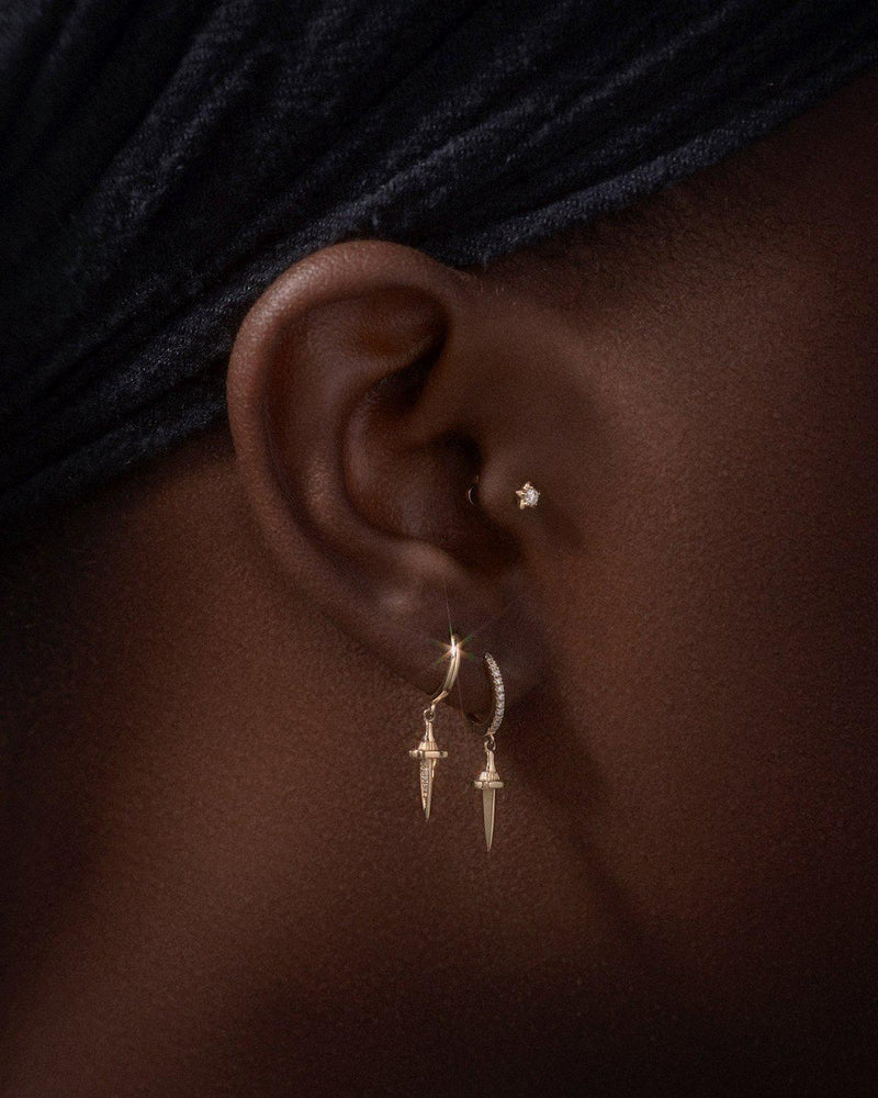 gold dagger earrings on the model