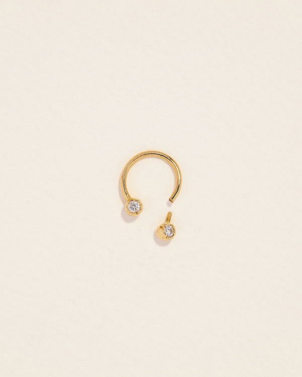 gold circular barbell piercing with two diamonds