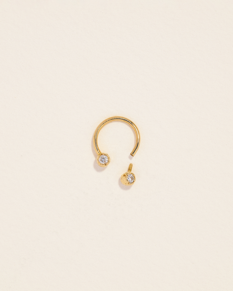 gold circular barbell piercing with two diamonds