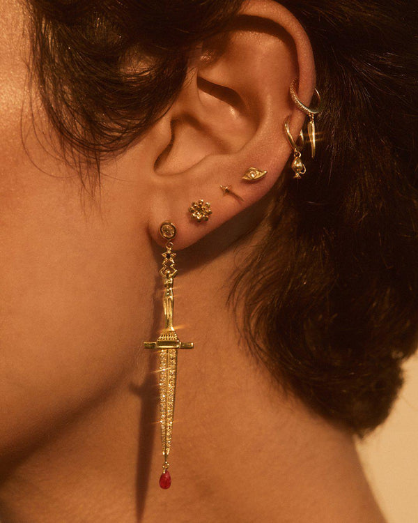 gold dagger earrings with ruby closeup on model