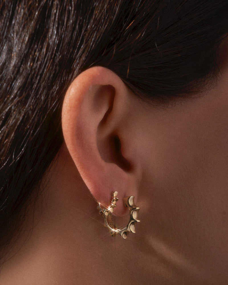 gold sun huggie earrings on the model